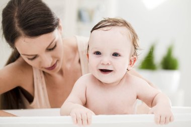 Anne bebeğini yıkıyor.