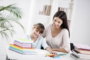 Anne ve kız birlikte ev ödevi yapıyorlar.