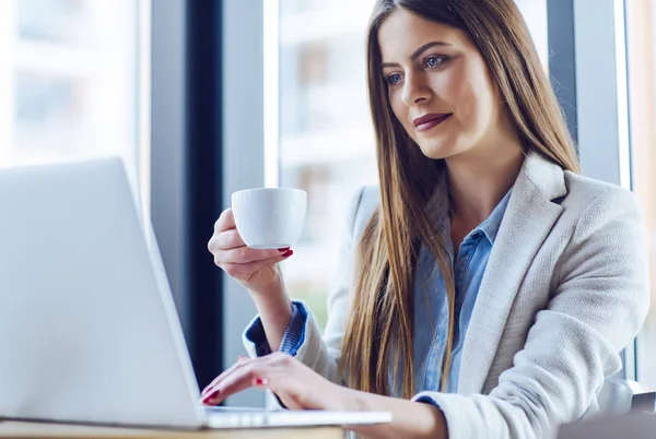 Schöne junge Frau arbeitet am Laptop — Stockfoto