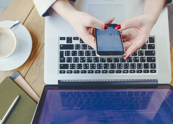 Mulher trabalhando no laptop e usando telefone — Fotografia de Stock