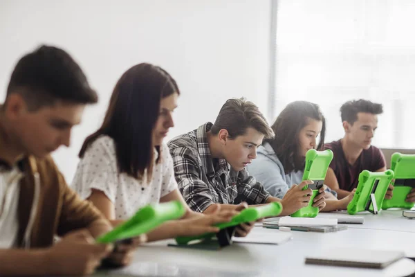 Estudantes do ensino médio usando tablets na sala de aula redonda — Fotografia de Stock