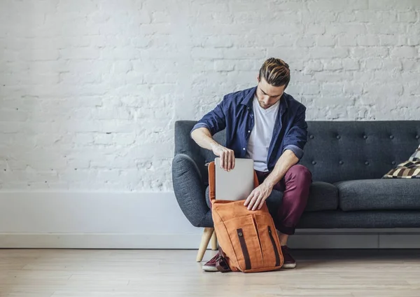 Homem colocando laptop na mochila — Fotografia de Stock