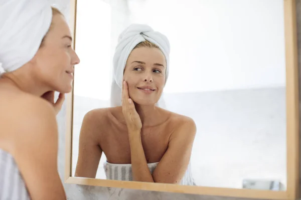 Mujer mirándose en espejo de baño — Foto de Stock