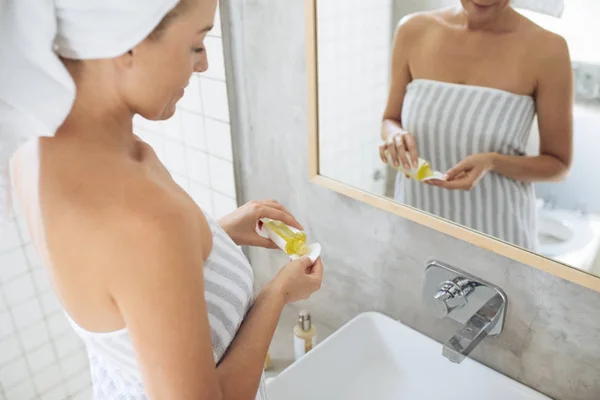 Mujer usando aceite cosmético —  Fotos de Stock