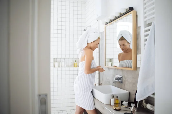 Vrouw met behulp van cosmetische in badkamer — Stockfoto