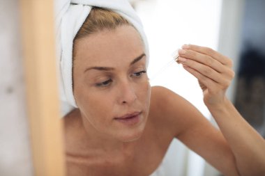 Kadının yüzündeki nemlendirici Serum uygulamak