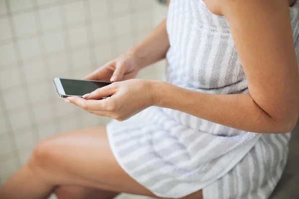 Mulher usando telefone celular no banheiro — Fotografia de Stock