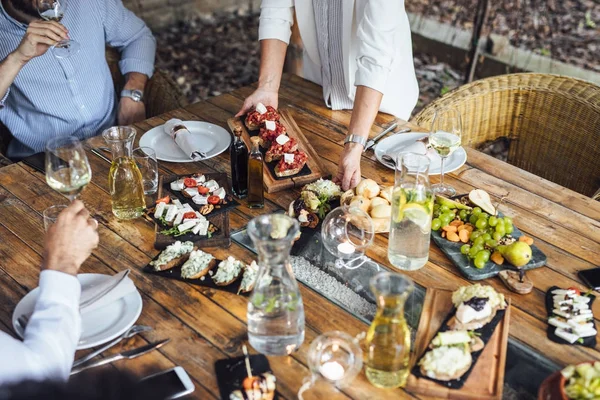 Dîner de femme hôte de fête servant de la nourriture à ses amis — Photo