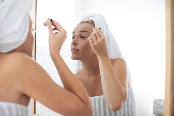 Mujer poniéndose suero cosmético en la cara — Foto de Stock