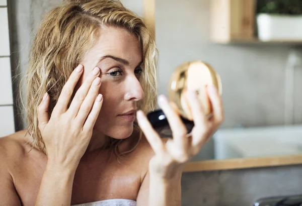 Mujer mirando su cara en el espejo — Foto de Stock