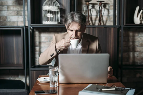 Бизнесмен читает на ноутбуке — стоковое фото