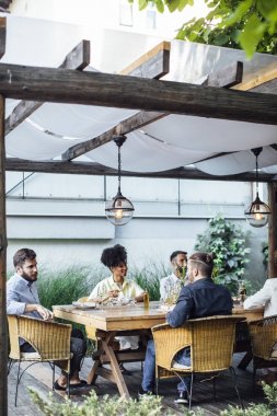 Çok ırklı bir grup gülümseyen insan açık oturma ve eğlenmeye zaman akşam yemeği parti kutlama.