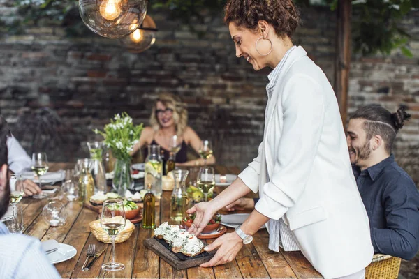 Mujer cena anfitrión sirviendo comida a sus amigos — Foto de Stock