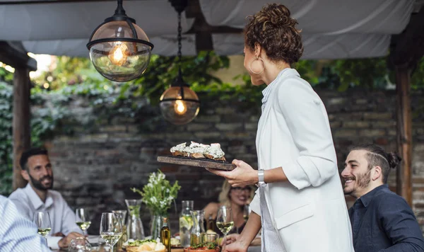 Gastgeberin einer Dinnerparty serviert ihren Freunden Essen — Stockfoto