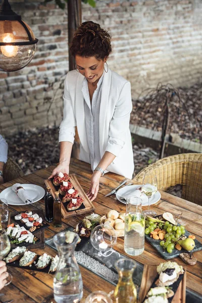 Donna cena partito ospitante servire cibo per i suoi amici — Foto Stock