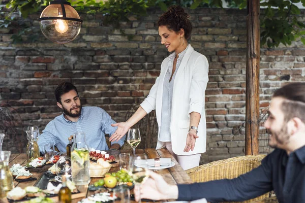 Dîner de femme hôte de fête servant de la nourriture à ses amis — Photo