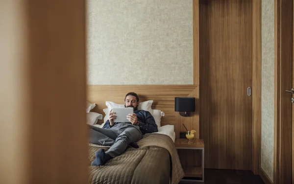 Homem deitado na cama e leitura em Tablet — Fotografia de Stock