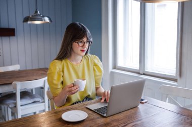 kahve dükkanında dizüstü bilgisayar kullanan kadın