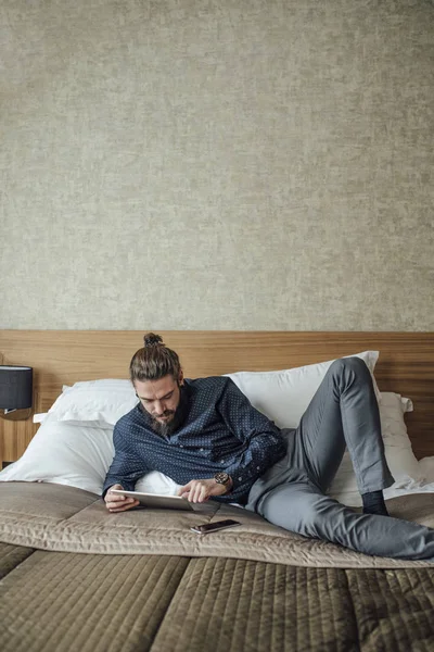 Mężczyzna leżał na łóżku i czytania na Tablet — Zdjęcie stockowe