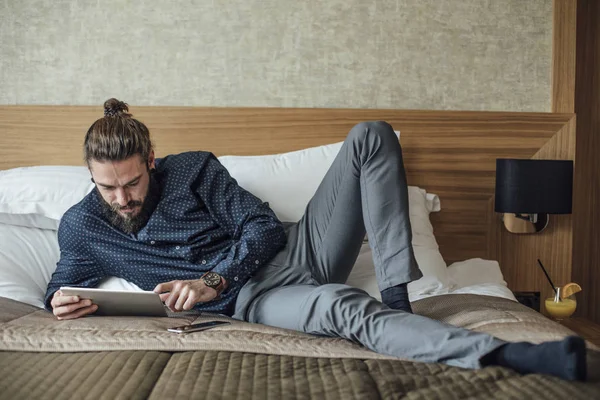 男性はベッドの上に横たわるとタブレットで読む — ストック写真