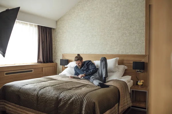 Man ligger på sängen och läsa på surfplatta — Stockfoto