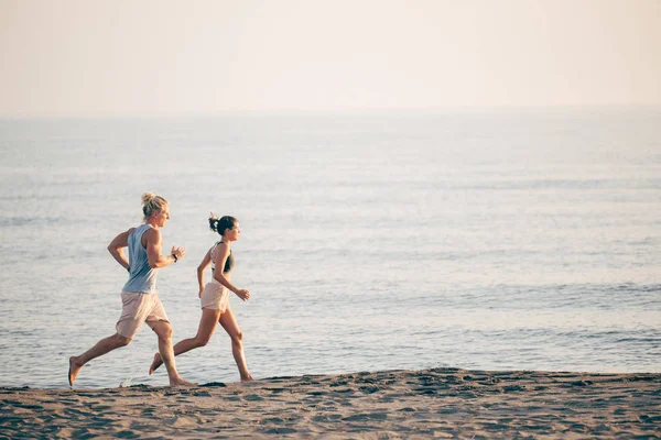 Homem e mulher correndo pelo mar — Fotografia de Stock