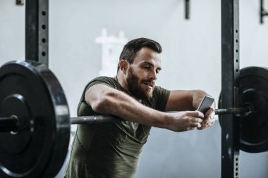 spor salonunda Smartphone kullanan adam