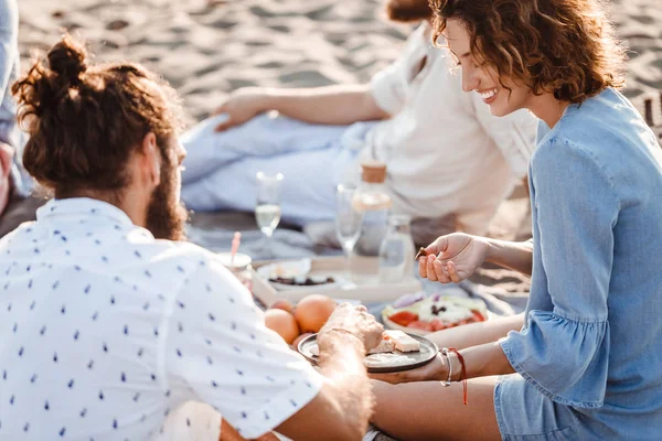 Pessoas desfrutando de comida em piquenique de praia — Fotografia de Stock