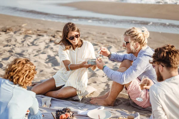 Pessoas desfrutando de comida em piquenique de praia — Fotografia de Stock
