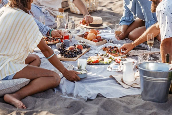 Människor som njuter av mat på stranden picknick — Stockfoto