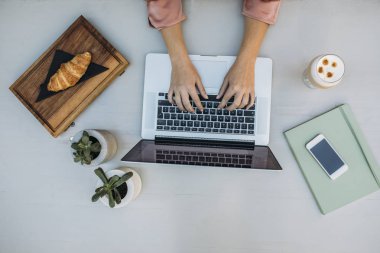 Kahve dükkanında dizüstü bilgisayarda yazarak bir kadın