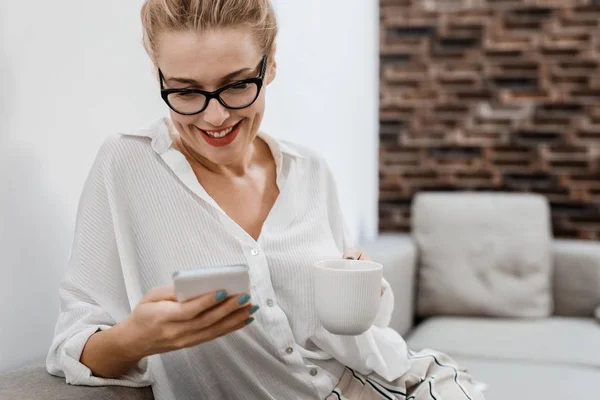 Vrouw met behulp van mobiele telefoon thuis — Stockfoto