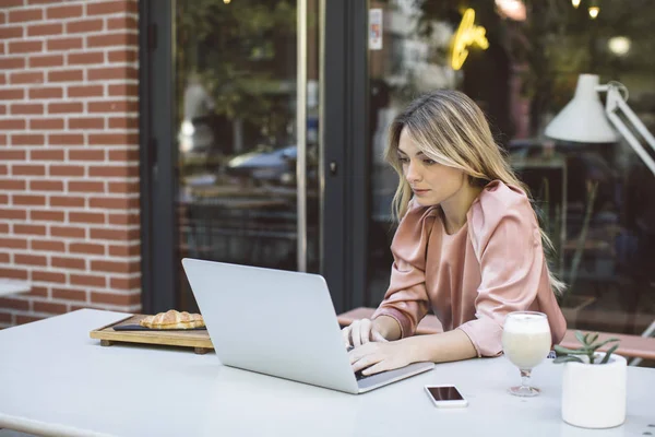 Женщина, печатающая на ноутбуке в кафе — стоковое фото