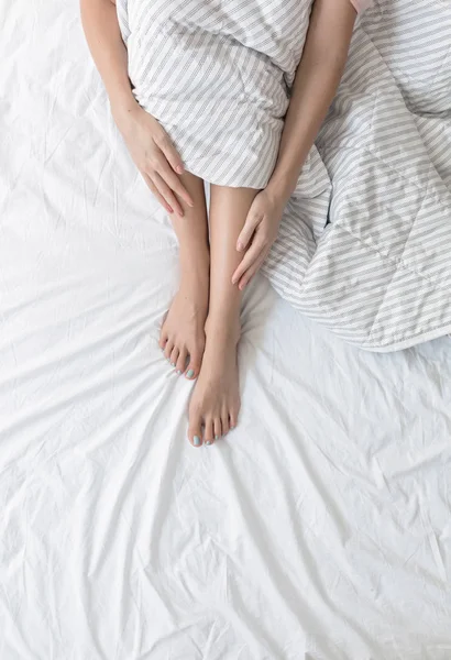 Kvinna sitter på sin säng — Stockfoto