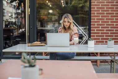 Kahve dükkanında dizüstü bilgisayarda yazarak bir kadın