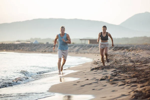 Мужчина и женщина бегут на пляж — стоковое фото