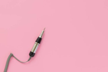 Pastel pembe arka planda elektrikli profesyonel çivi manikür makinesi.