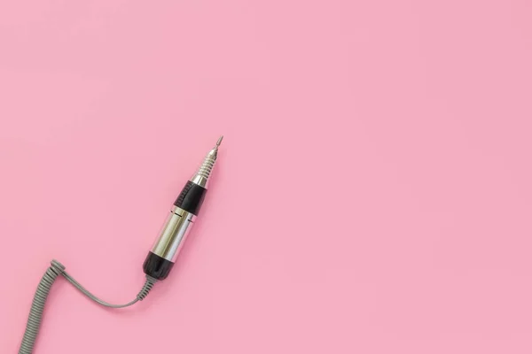 Pastel pembe arka planda elektrikli profesyonel çivi manikür makinesi.