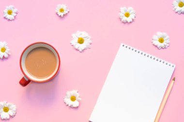 İçinde kahve fincanı, kalem ve pastel pembe arka planda çiçekler olan boş bir defter. Yaz ya da bahar kompozisyonu. Resim kopyalama alanı, üst görünüm, düz uzanma