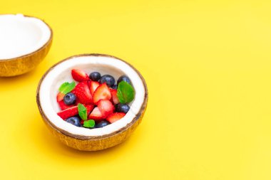 Sarı arka planda taze meyveli hindistan cevizi kasesi.