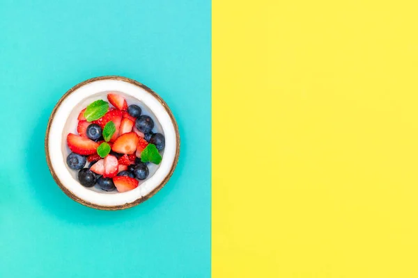 青と黄色の幾何学的背景に新鮮な生の果実とココナッツボウルと創造的な組成物 — ストック写真