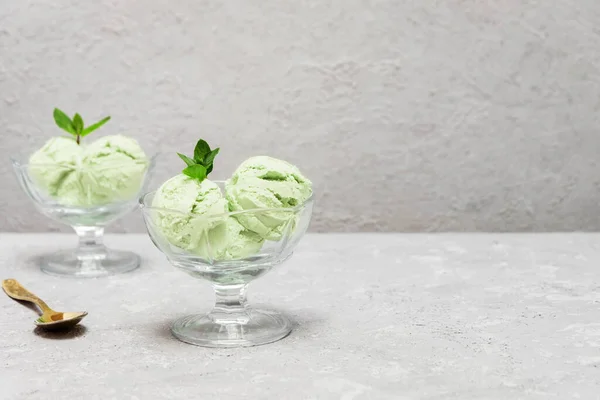 Homemade vegan avocado ice cream in glass cups on neutral background with copy space