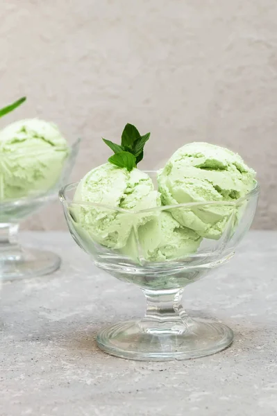 Homemade green avocado ice cream decorated with mint leaves on concrete background, copy space