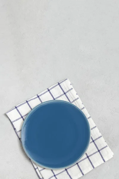 Piastra blu vuota con tovagliolo su sfondo neutro in cemento — Foto Stock