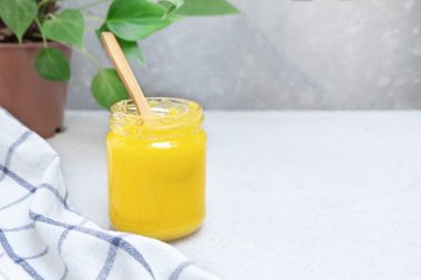 Tarafsız bir arka planda cam bir kavanozda açık bir tereyağı.