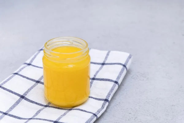 Homemade clarified butter in a glass jar on neutral background — Stock Photo, Image