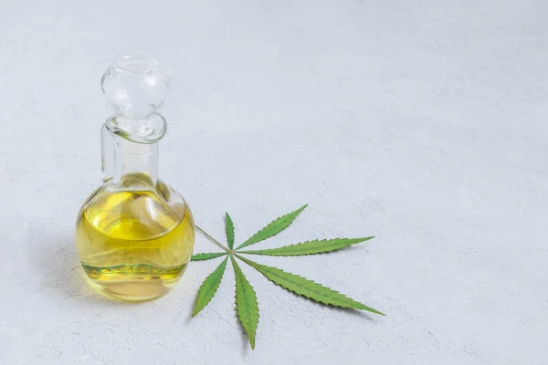 Cam şişede esrar CBD yağı ve nötr ışık arka planında marihuana yaprağı ve metin için boşluk