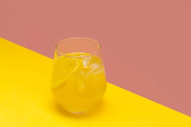 Bağışıklık artırıcı buzlu limonlu zencefilli zencefilli çay, pembe ve sarı arka planda cam bir fincanda, metin için yeri var.