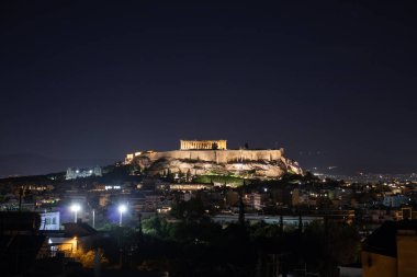 Atina 'da ışıkları ve güzel manzarası olan bir tepedeki akropolis binasının gece manzarası