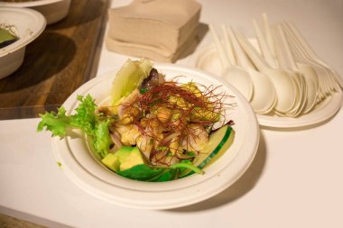 Tek kullanımlık bir tabakta avokado, safran, salatalık ve nohut ile yeşil vejetaryen salatası.